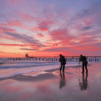 Zwei Fotografen am Strand bei atemberaubenden Sonnenuntergang.